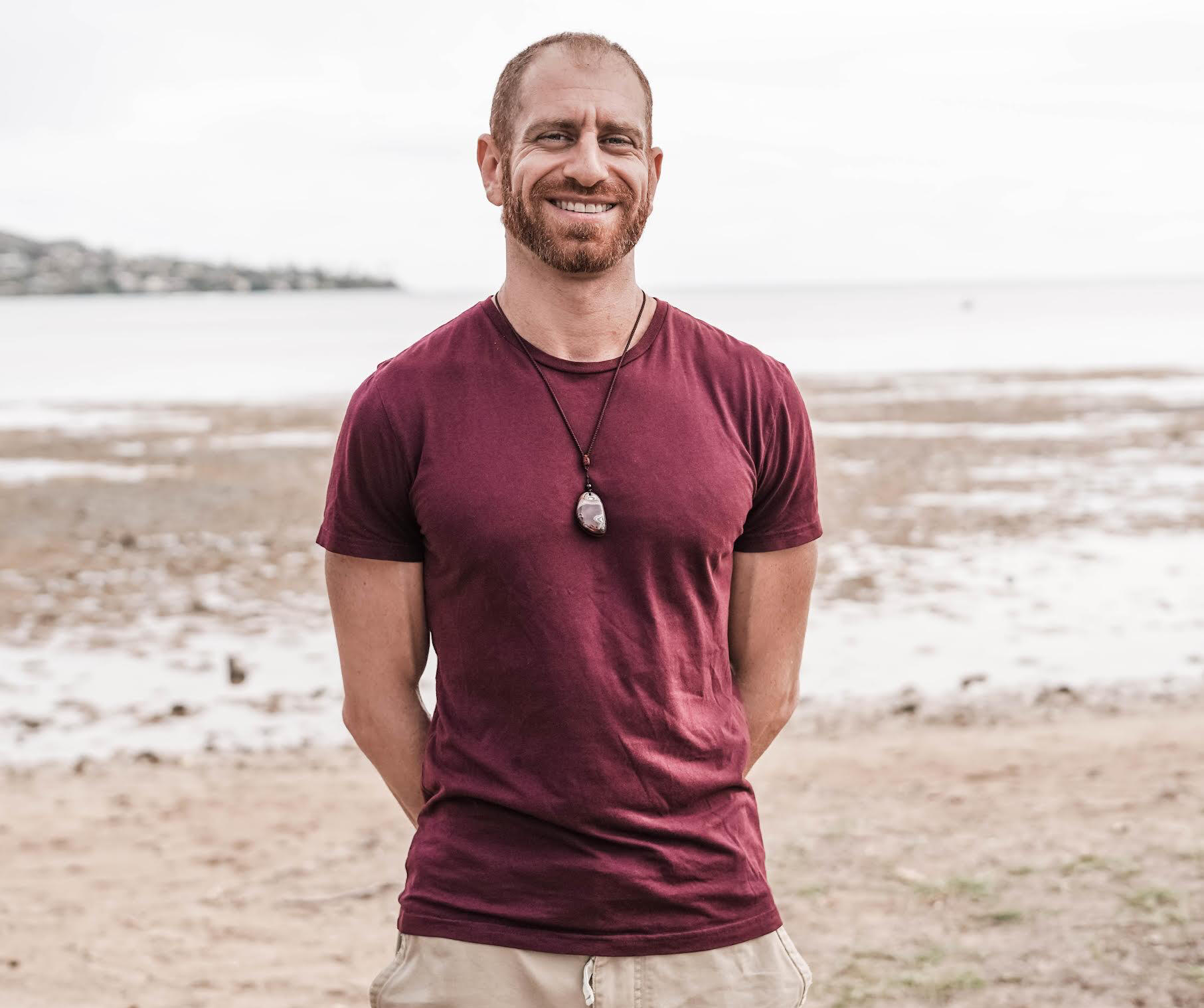 Image of Jay from Mokulua Massage standing in front of the ocean happy and confident.